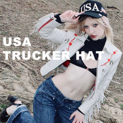 A person wearing a black trucker hat with 'USA' text on it, posing outdoors.